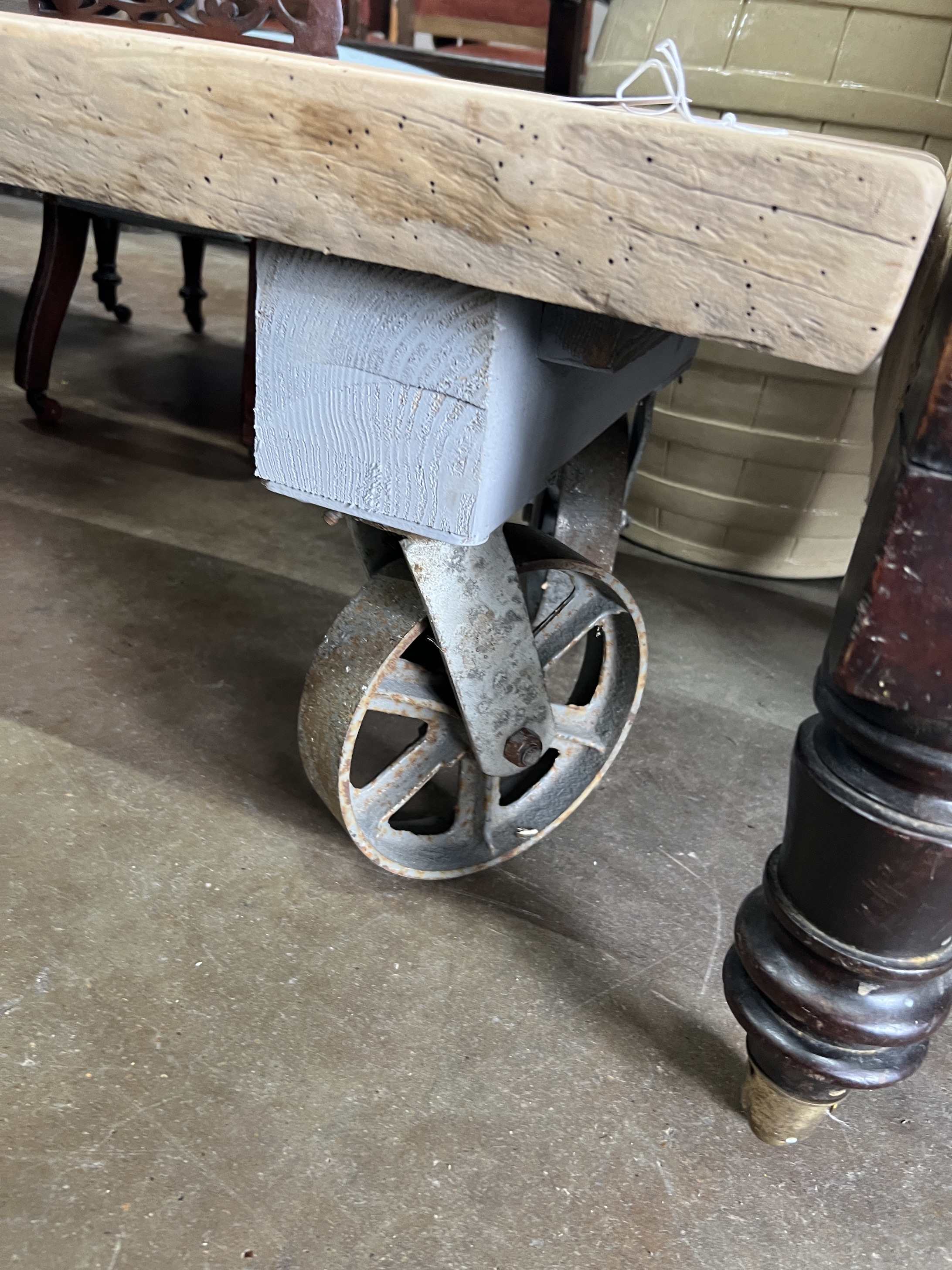 An industrial style rectangular waney edge plank top coffee table on spoked wheel base, width 122cm, depth 53cm, height 39cm
